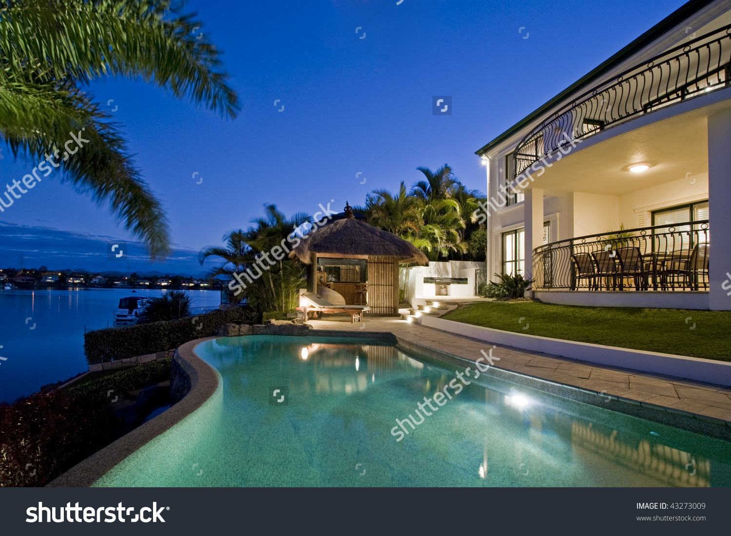 stock-photo-luxurious-mansion-exterior-at-dusk-overlooking-pool-canal-and-bali-hut-43273009